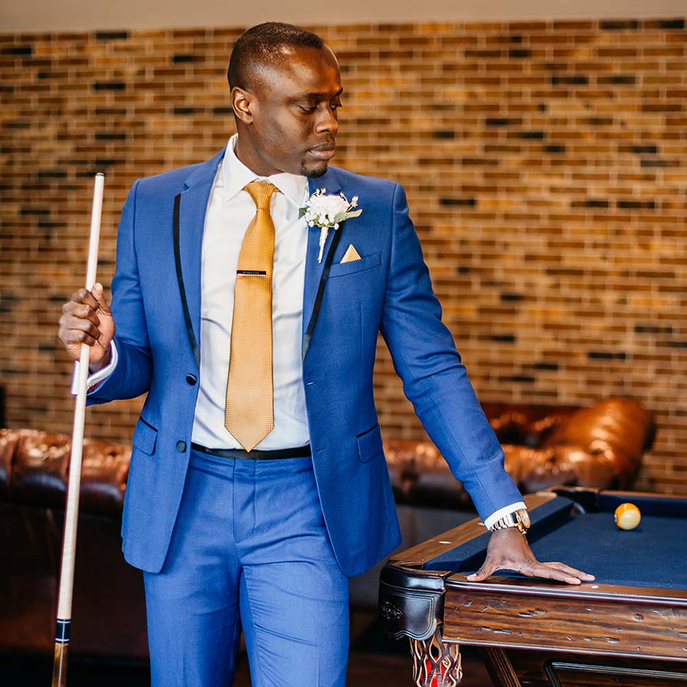 Groom posing while leaning a pool table